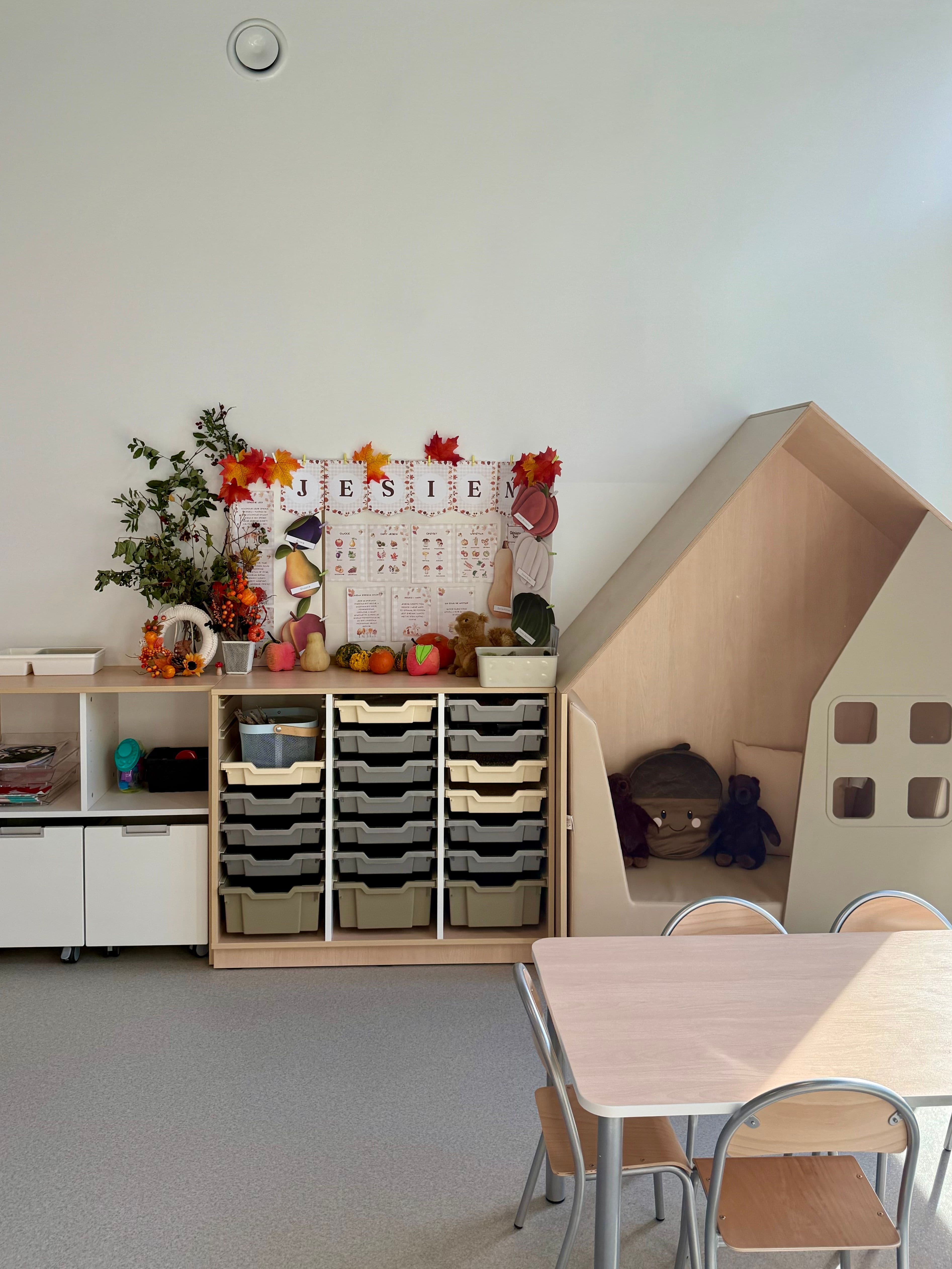 Sala edukacyjna z niskimi stolikami i jesienną dekoracją